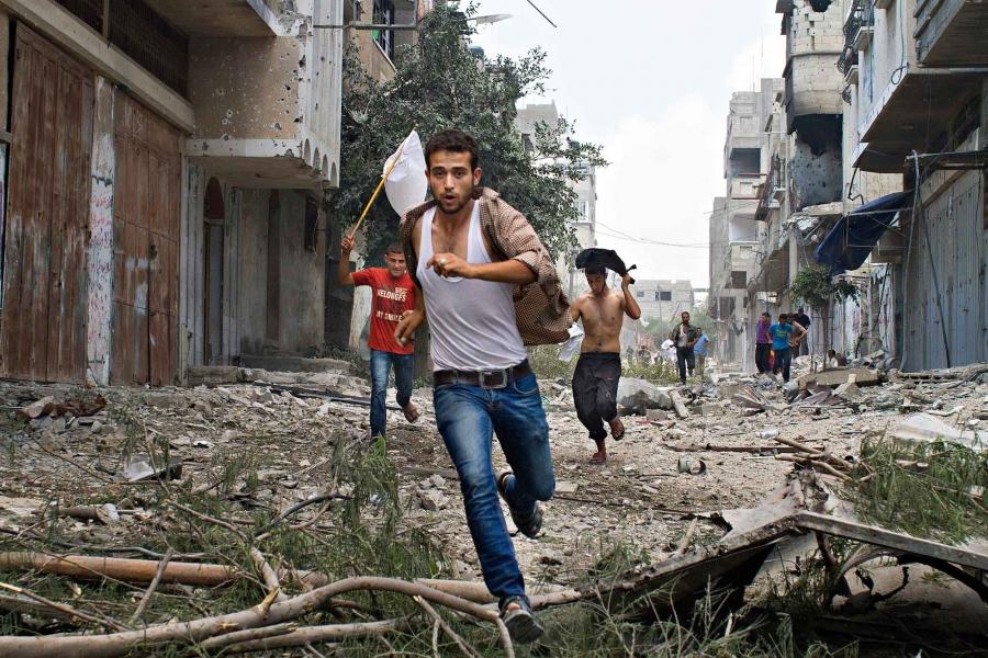 Palestinian men run with a white flag in the Shejaia neighborhood, which was heavily shelled by Israel during fighting, in Gaza City, July 20, 2014. At least 50 Palestinians were killed on Sunday by Israeli shelling in the Gaza neighborhood, and thousands