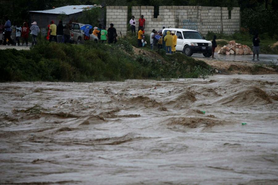 People inspect the rising water level of a river due to the rains caused by Hurricane Matthew passing through Port-au-Prince, Haiti.