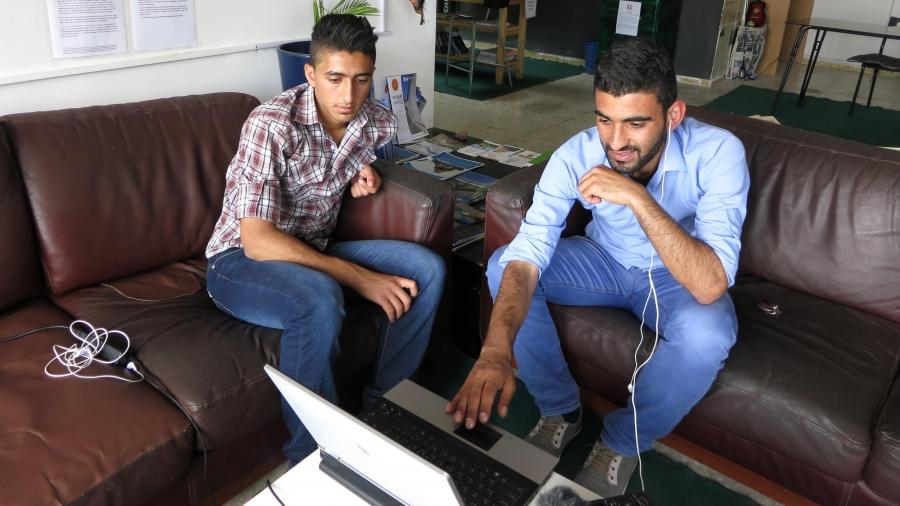 Mohammad (r) watches Fauda on a computer with his cousin at the youth hostel in Ramallah where they both work. 