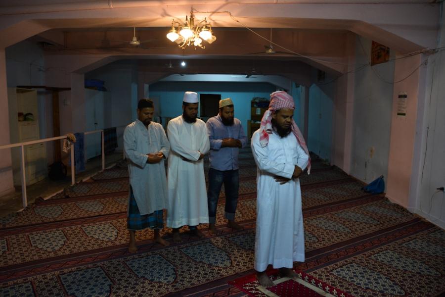 Men from Bangladesh pray on a Friday afternoon at the Hazrat e Umar prayer room in the neighborhood of Kato Patisia, Athens.
