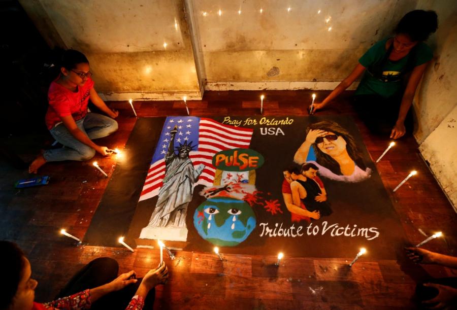 Students light candles around a rangoli, or mural made out of colored powders, for the victims of the shooting in Orlando in Mumbai, India. 