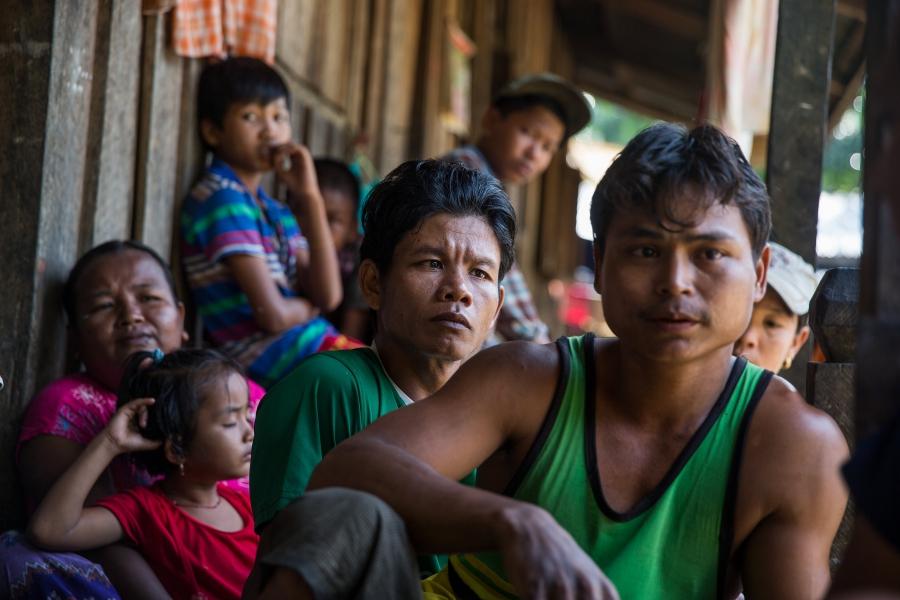Workers and their families, including Zaw Myo Htike (foreground in green sleeveless shirt), gather on their porches at a small village where migrant workers for Supowin Palm Oil live outside Kawthaung, Myanmar, Nov. 14, 2016. Many workers on this plantati