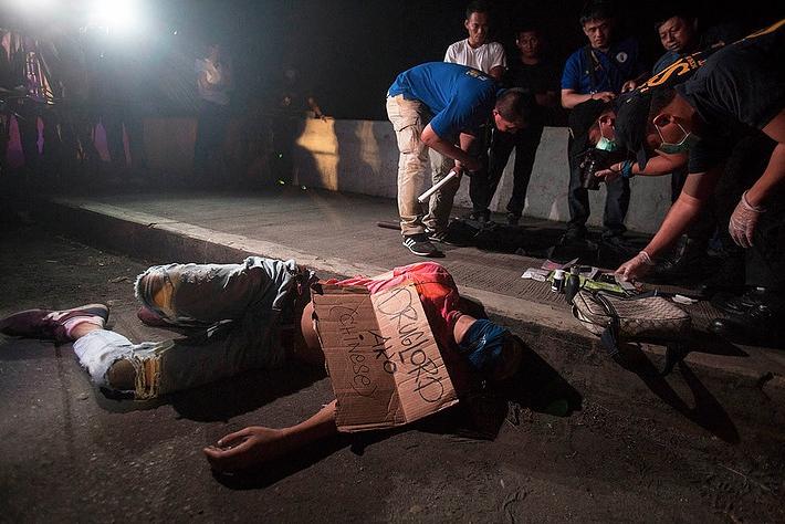 A victim of summary execution, with packing tape wrapped around his head and a sign on his chest that reads, “I am a Chinese drug lord,” found along Road 10 in Manila.