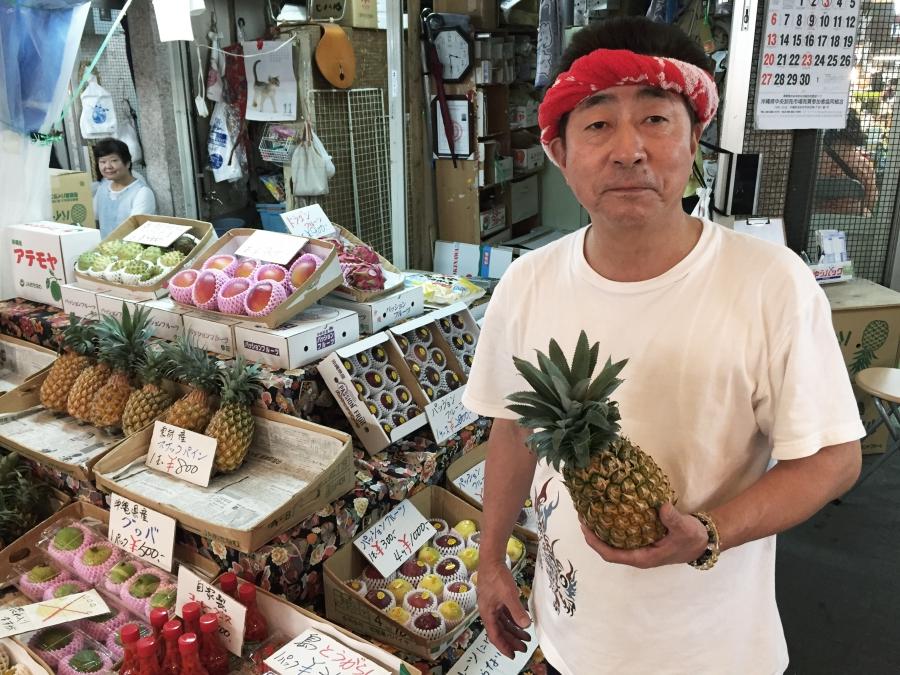 Yoshio Noda sells pineapples at a covered market in Okinawa's capital city, Naha. He thinks US President-Elect Trump will tone down his stance on withdrawing US troops once he learns how much Japan is paying.