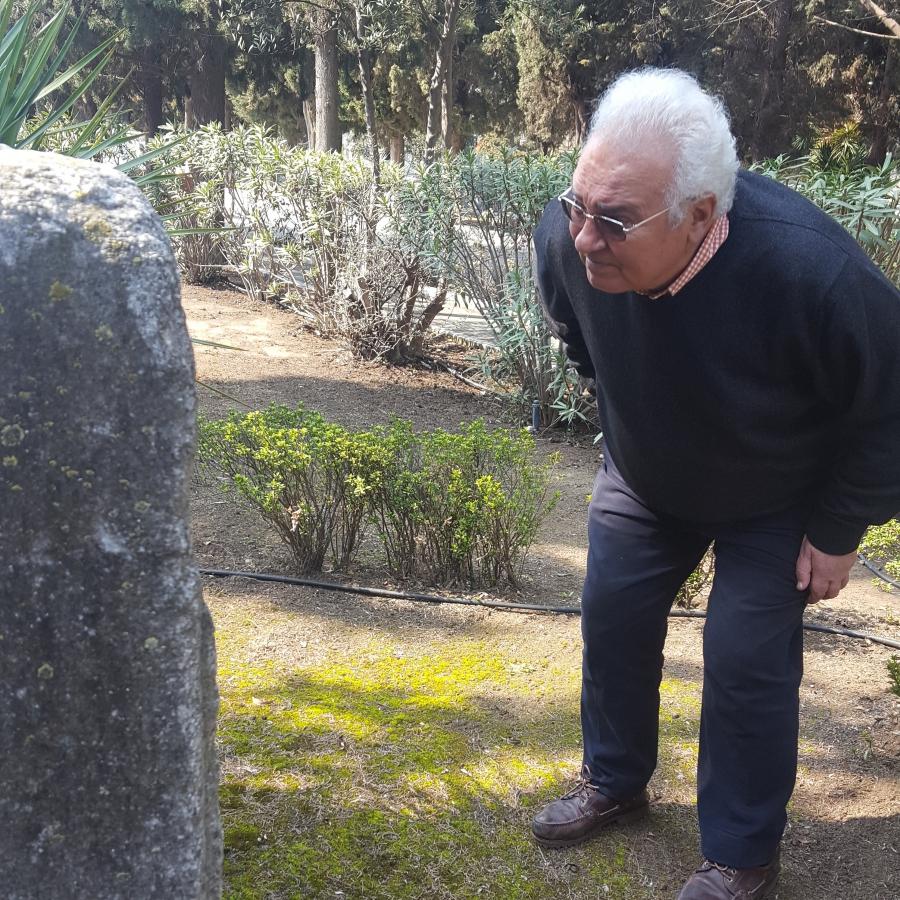 Jacky Benmayor stoops down to get a better look at an old tombstone at the newer Jewish cemetery.  