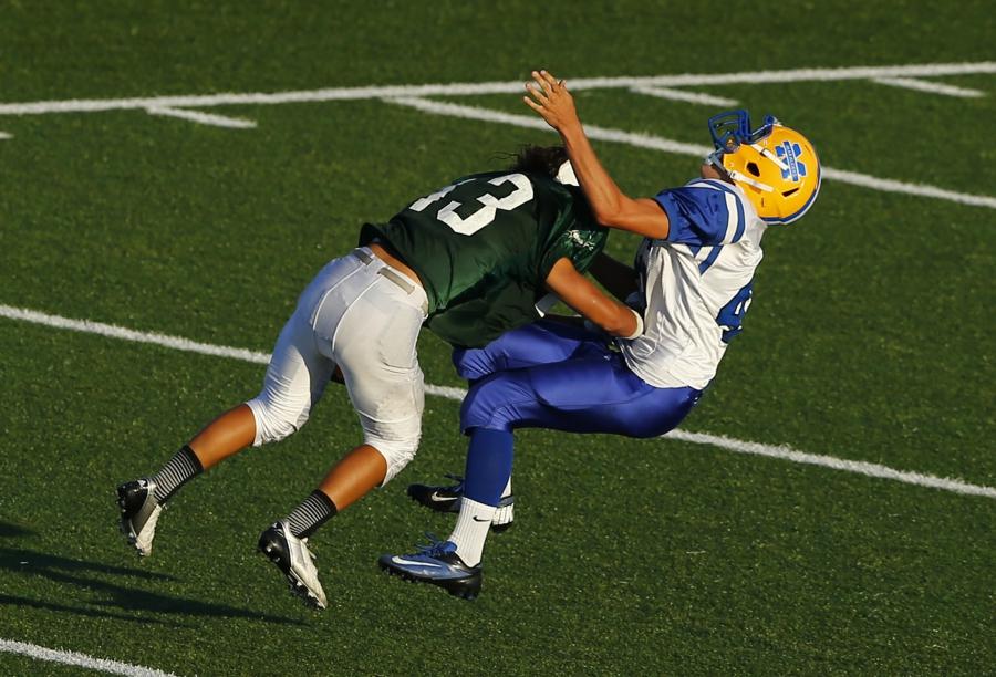 A Mira Mesa Junior Varsity high school football player trying to punt the ball is hit to the turf by an Oceanside Pirates player during their game in Oceanside, California September 14, 2012.
