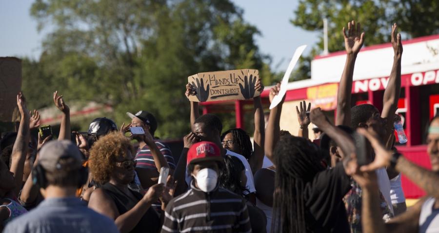 Demonstrators raise their hands while protesting the shooting death of teenager Michael Brown in Ferguson, Missouri, on August 13, 2014.