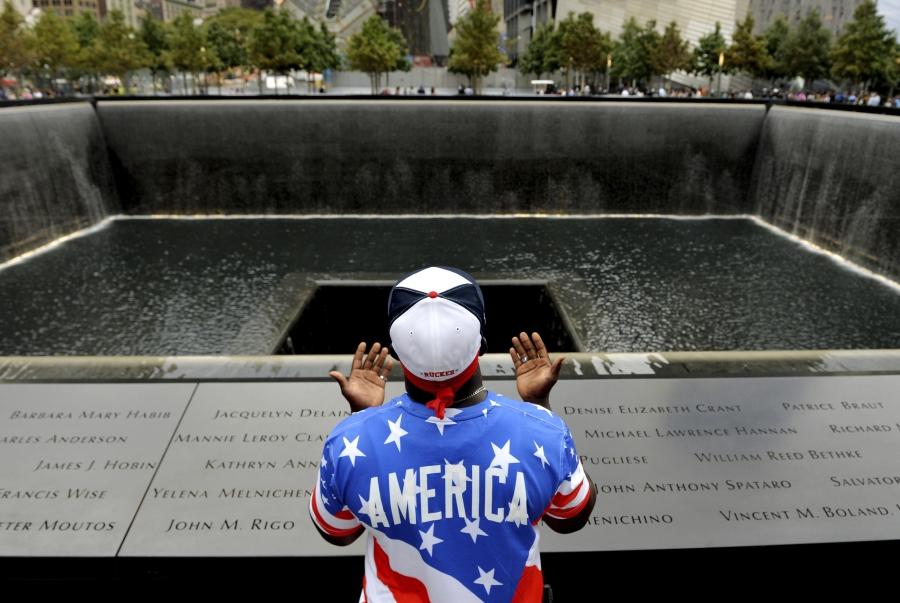 Man praying in front of memorial