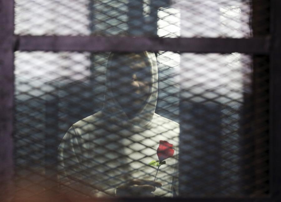 A defendant holds a rose during the retrial of 21 activists on charges of breaking a law that bans protests without a police permit, in Cairo, Feb. 12, 2015