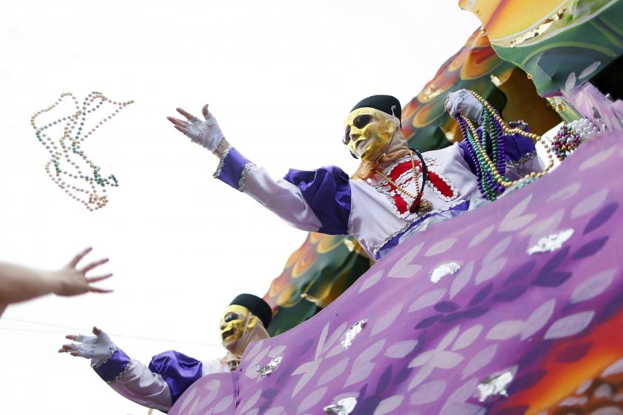 A member of the Krewe of Thoth throws beads during a Mardi Gras parade in New Orleans, Feb. 15, 2015.