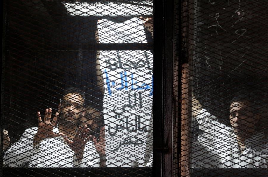 Egyptian journalists behind bars during a court trial outside Cairo