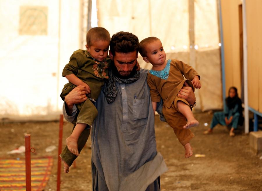 An Afghan refugee holds his children after arriving at a UNHCR registration center in Kabul, Afghanistan, Sept. 27, 2016.