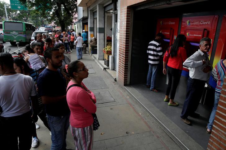 ​People line up to withdraw cash from an automated teller machine (ATM) outside a Banco de Venezuela branch in Caracas, Venezuela November 25, 2016. Picture taken November 25, 2016. 