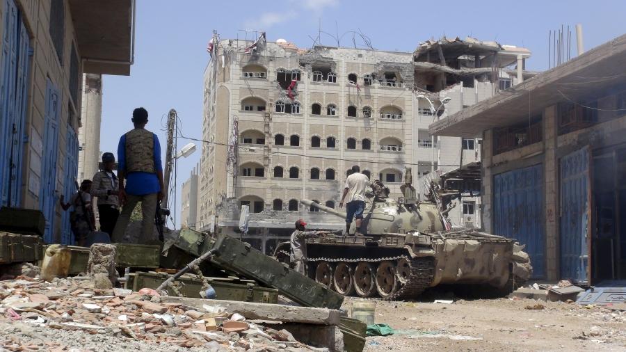 Anti-Houthi fighters of the Southern Popular Resistance stand near a tank in Yemen's southern port city of Aden