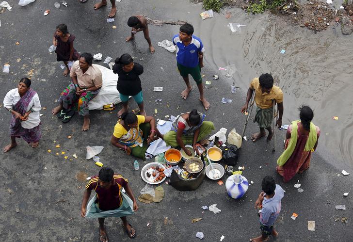 ​Displaced residents cook their meal on a flooded roadside in Chennai, India, December 3, 2015. 