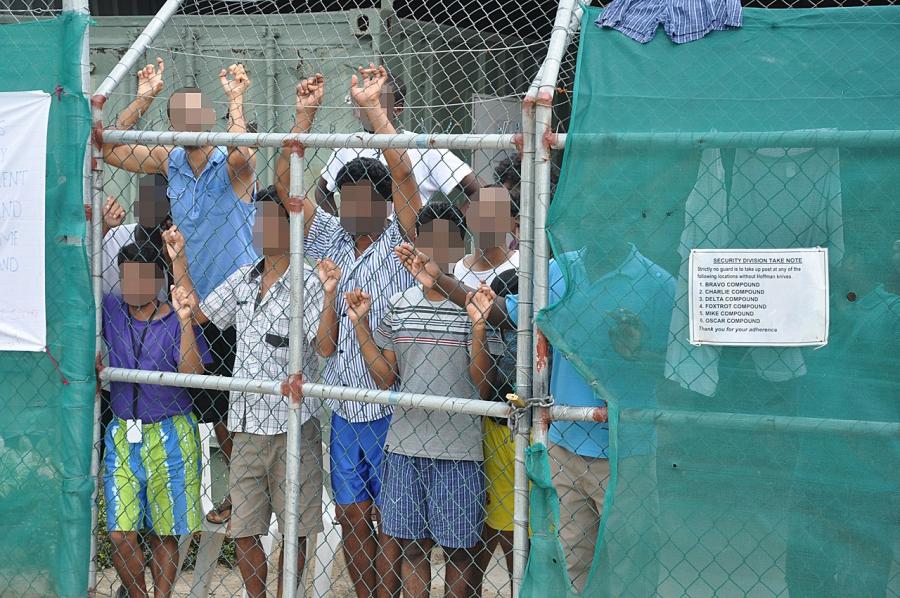 Asylum-seekers look through a fence at the Manus Island immigration detention camp on Papua New Guinea. Manus Island is one of two offshore detention camps funded by the Australian government to house migrants intercepted at sea. Some of the asylum seeker