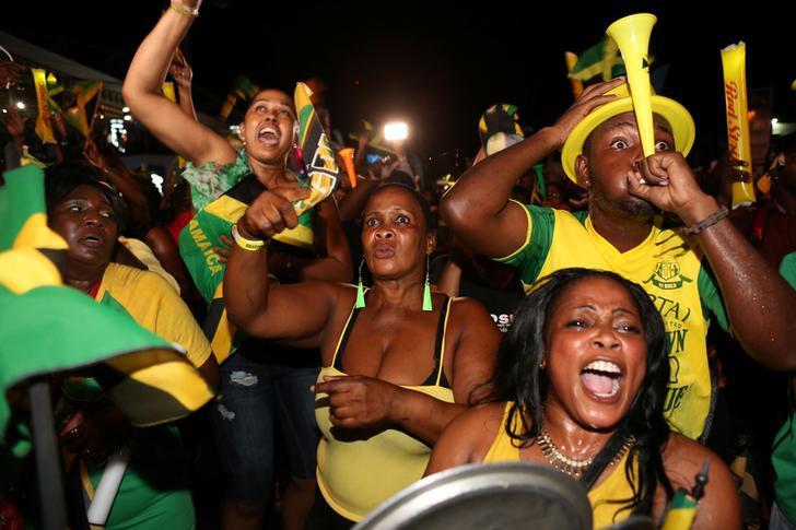Fans cheer while watching a broadcast of Jamaica's Usain Bolt winning the men's 100 meters final and becoming the first man to win three successive Olympic titles on the track, in Kingston, Jamaica, August 14, 2016.
