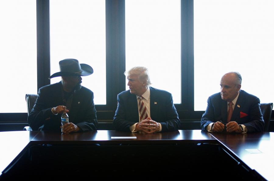 Three men at a table, one on left in cowboy hat