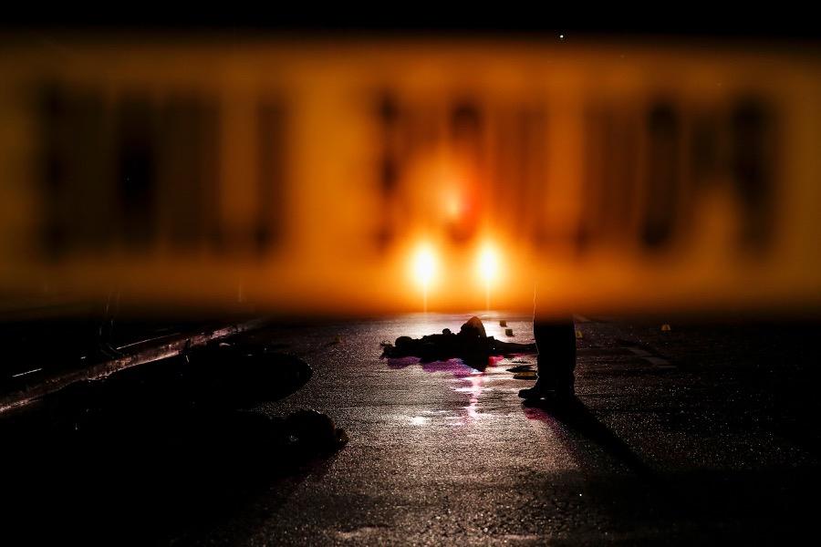 The bodies of two men are lit by a police car in Manila, Philippines