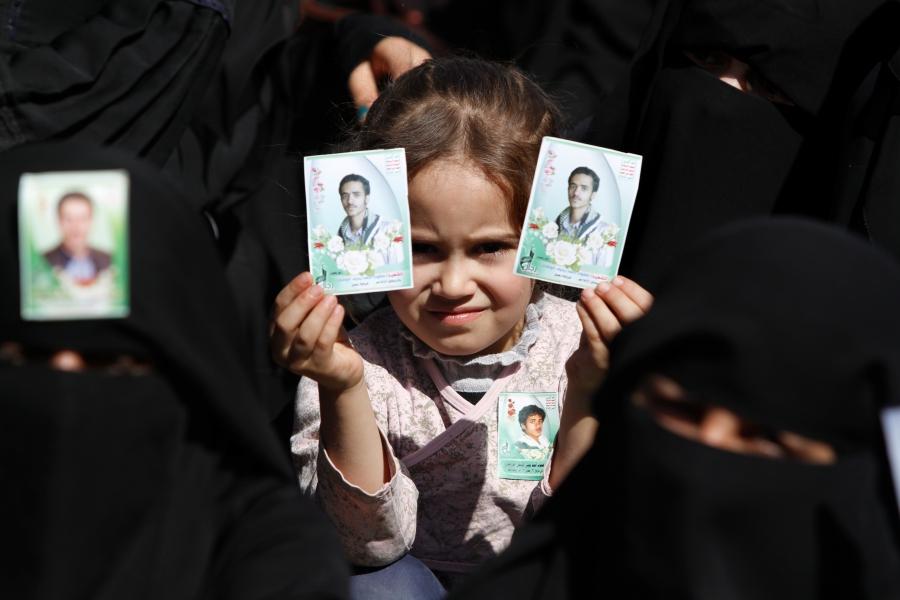 A girl holds up a picture of a relative killed while fighting with the Houthi rebels
