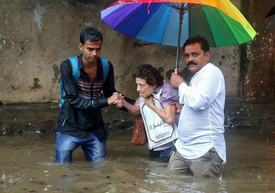 A woman is helped to move through a water-logged road after rains in Mumbai.