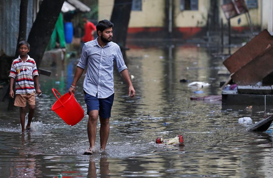 A man carrying a bucket walks through a water-logged neighbourhood in Mumbai.
