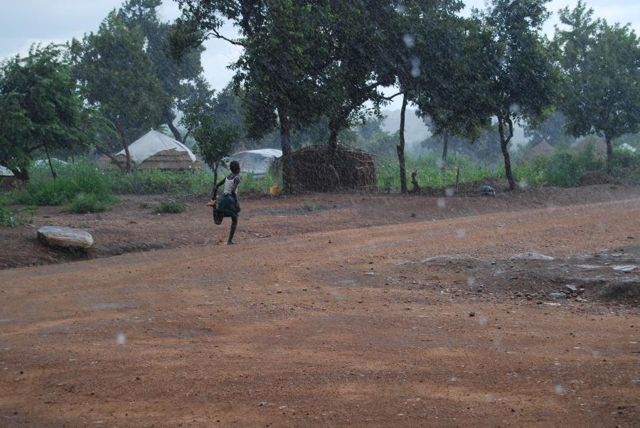 A girl runs through an afternoon rainstorm in Bidi Bidi. The rains, which come daily during certain times of the year, can flood the refugee settlement's dirt roads.
