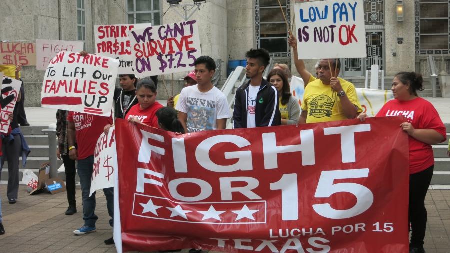 Mario Sidonio, left, and Daniel Meza standing behind a sign at a Houston rally for a $15 an hour minimum wage.