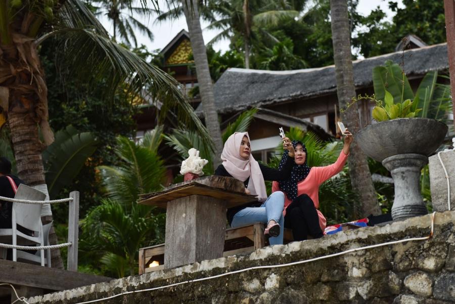 Women in hijab take selfies on their mobile phones at Casa Nemo Resort and Spa.