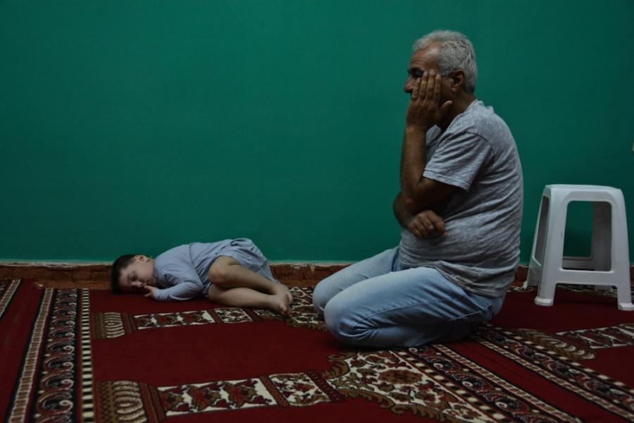 Mohammad, a 5-year-old boy from Syria, takes a nap before the night prayer on the floor of a makeshift mosque in the Attiki neighborhood in Athens.