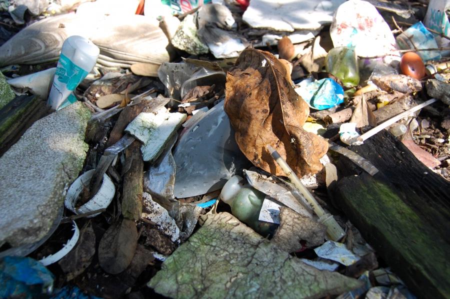 A syringe sits on top of other garbage lining the shores of Rio's Guanabara Bay