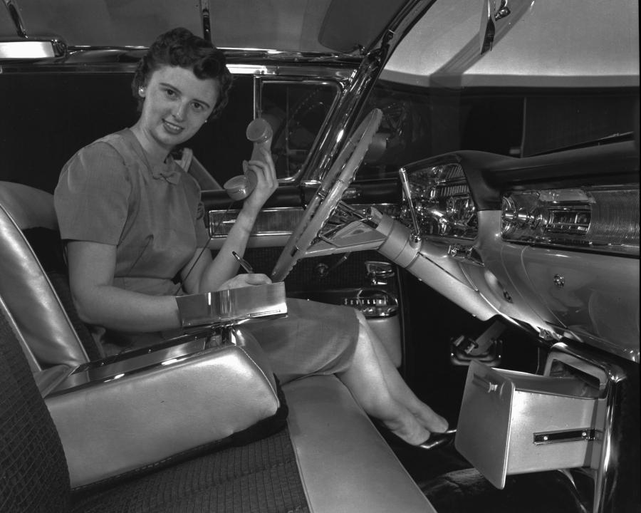 Suzanne Vanderbilt demonstrating an early car phone and built-in memo pad — custom features for her 1958 exhibition-model Cadillac Eldorado Seville.