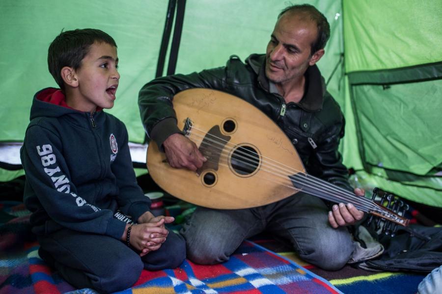 Omar Thaljey, 9, singing as his father Enwar plays the oud, at Idomeni camp.