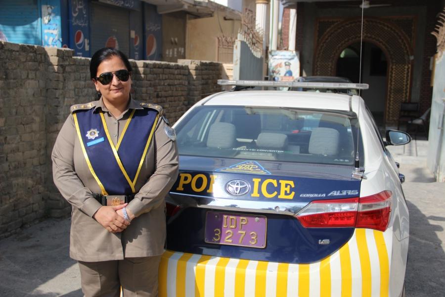 Asima Naqvi stands with her patrol car.