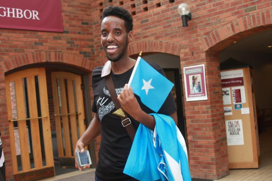 Young man holding a Somali flag and his smartphone