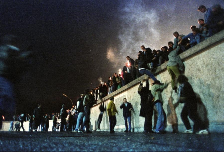 East German citizens climb the Berlin Wall at the Brandenburg Gate after the opening of the border was announced early Nov. 9, 1989. 