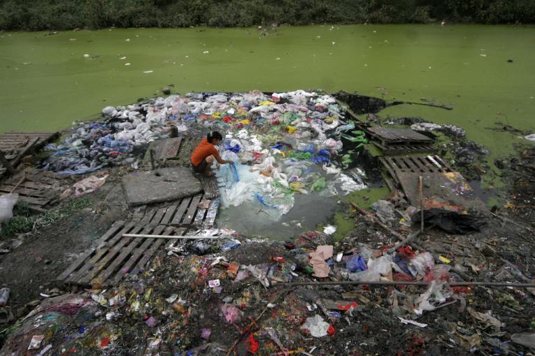 A woman washes plastic in a river in Tianjin, China, Sept. 13, 2007.  