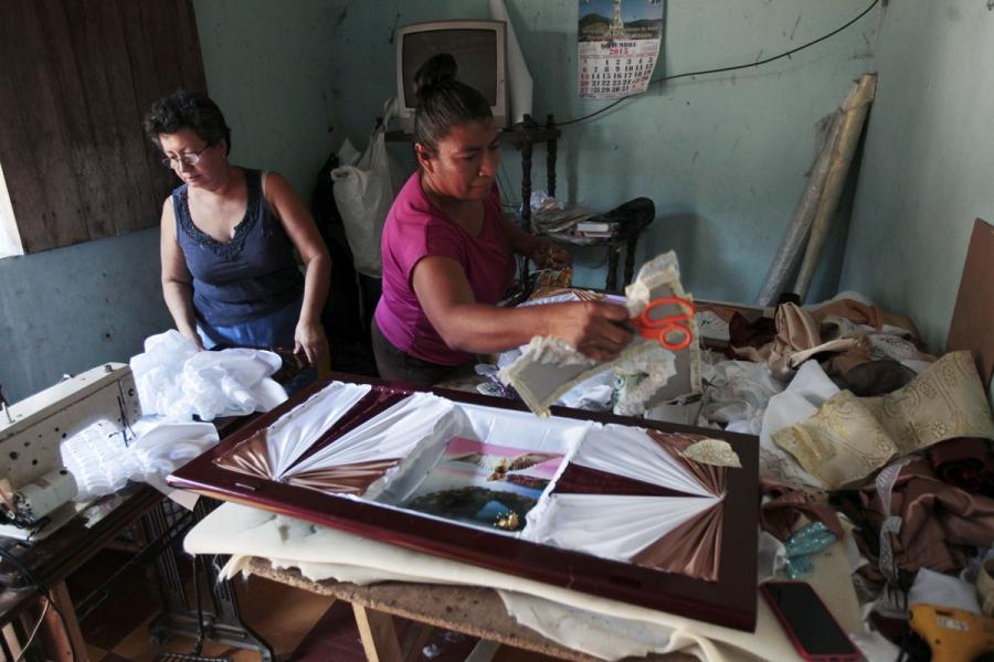 Women work on details of a coffin at El Nuevo Renacer factory in Jucuapa.