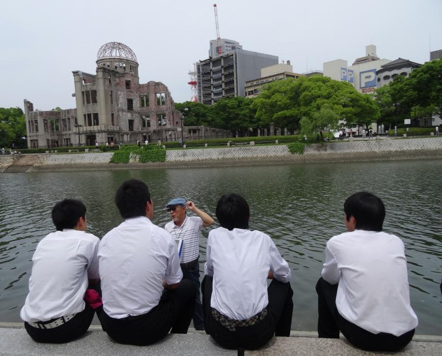 A volunteer guide speaks to school students across the river from the Atomic Bomb Dome in Hiroshima's Peace Memorial Park. 
