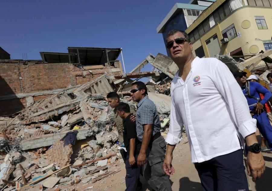 President Rafael Correa walks past a collapsed building