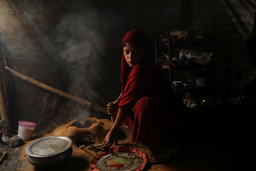 Shofika Begum cooks inside their temporary shelter at the Kutupalong refugee camp.
