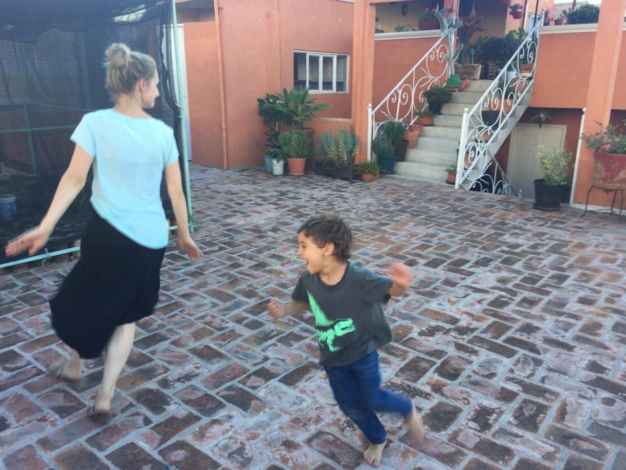 Young boy chases woman on cobblestone terrace