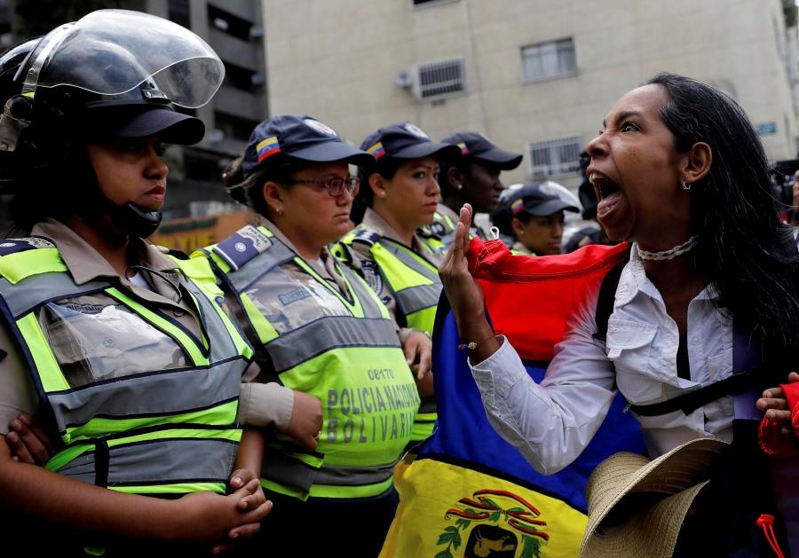A demonstrator shouts slogans in front of police officers during a women's march in Venezuela