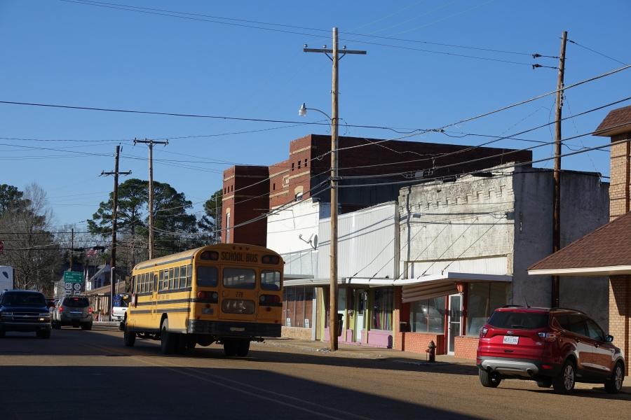 Small town street with bus in front, empty storefronts behind