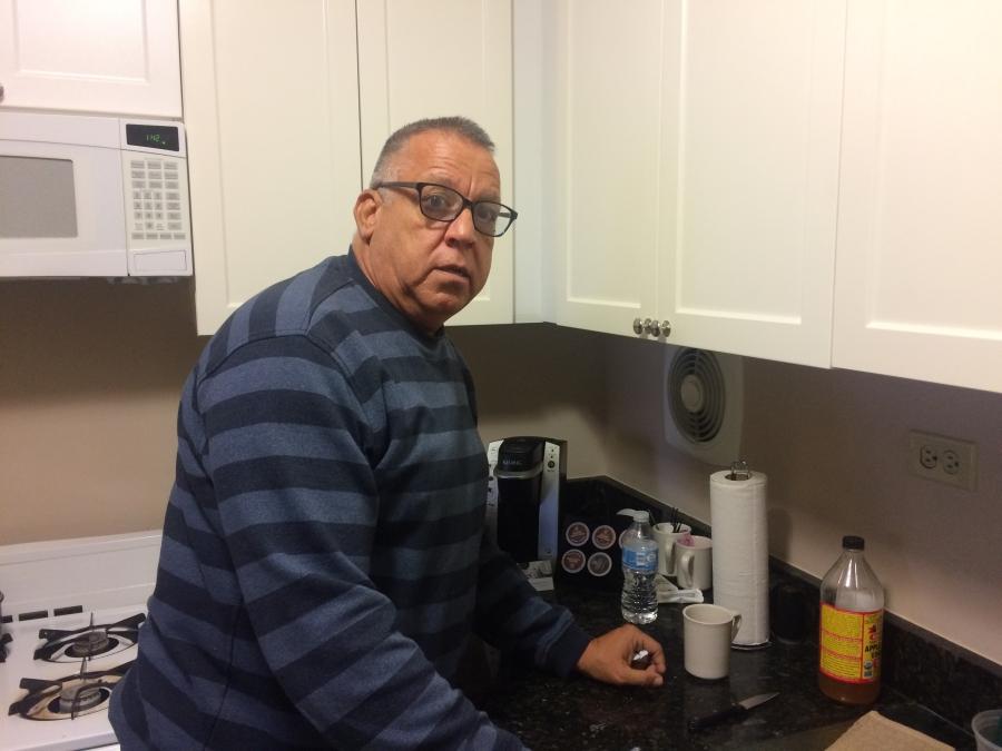 Carlos Torres makes coffee in the kitchen of his hotel room.