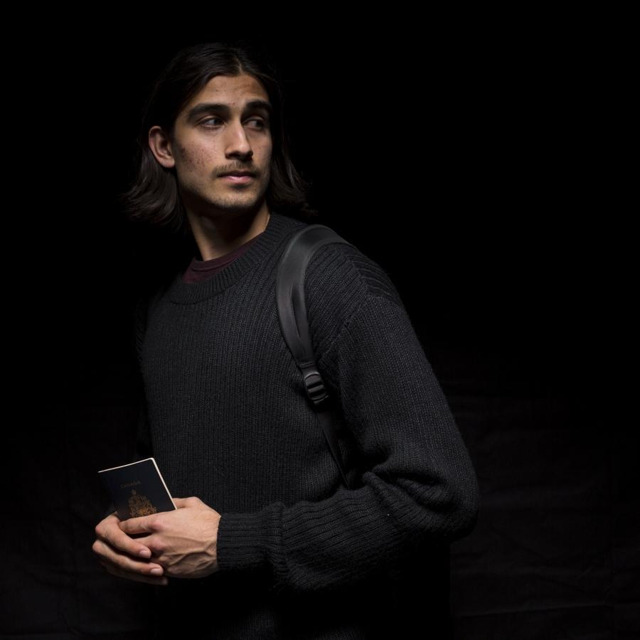 Young man with backpack and tablet, against a black background