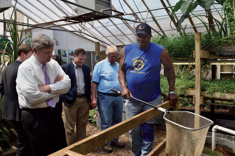 Will Allen demonstrates his aquaculture system for Agriculture Secretary Tom Vilsack (left) in 2015. 