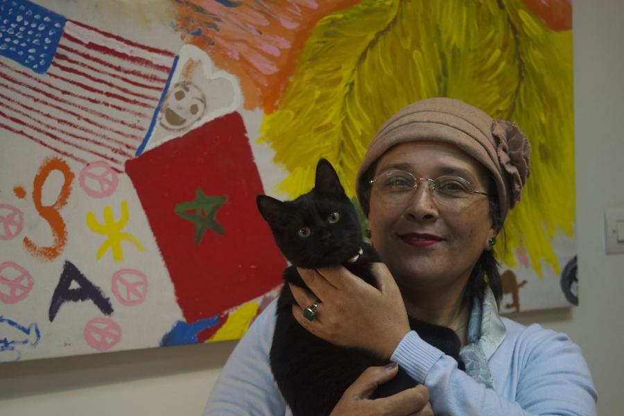Jamila Bargach and he cute cat in front of a mural 