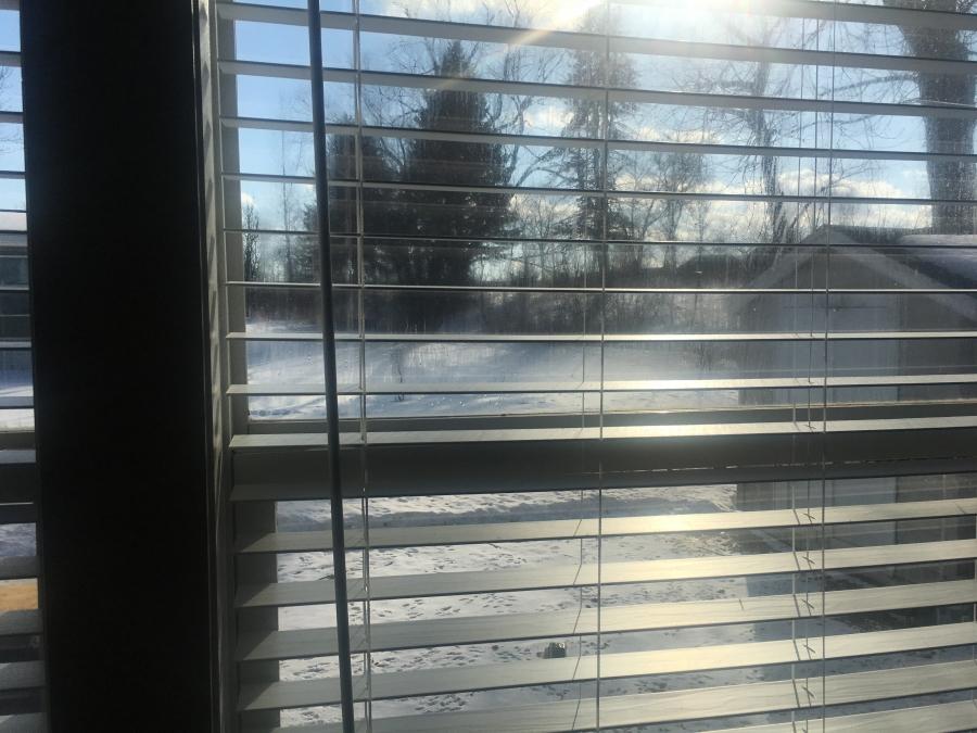 Shutters on window look out onto snow area in front of house