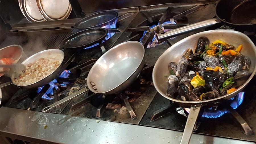 Three burners on commercial stove, cooking food